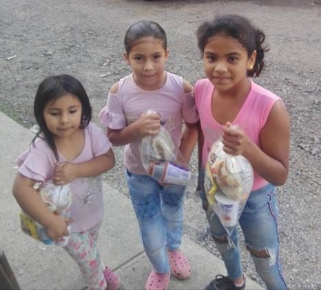 Tres niñas con sus bolsas de alimentos